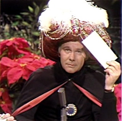 Johnny Carson as the Amazing Karnak, holding an envelope to his head.